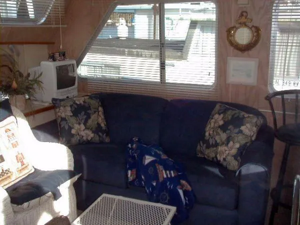 Slide: The Image of Cozy 1992 Holiday Mansion houseboat interior with blue sofa, floral pillows, and nautical decor. - 3