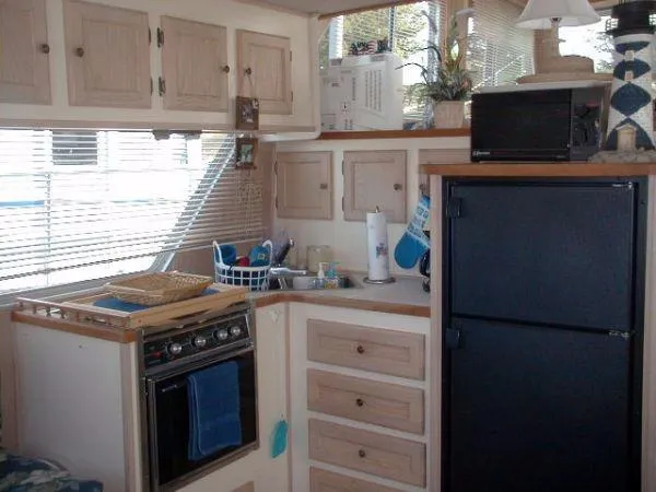Slide: The Image of 1992 Holiday Mansion houseboat kitchen with stove, fridge, cabinets, and decor. - 7