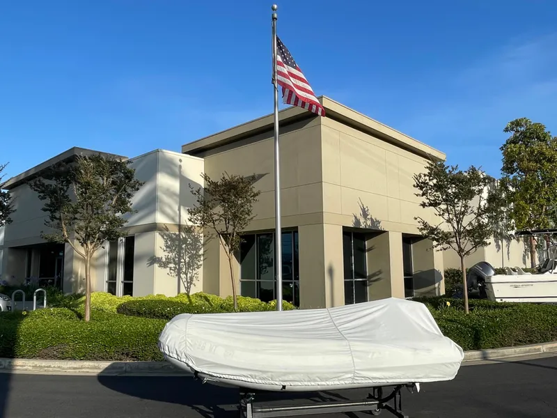 Slide: The Image of 2019 AB Inflatables Navigo 9 VS covered boat on trailer outside building with American flag. - 9