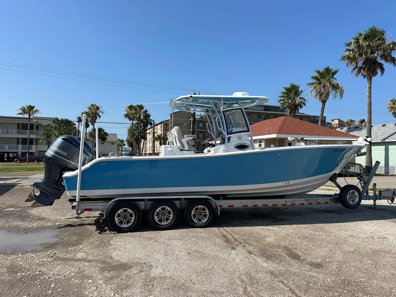 Slide: The Image of 2021 Sportsman Open 282 Center Console boat on a trailer in a coastal area. - 0
