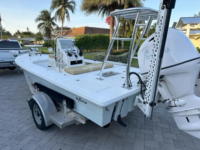Slide: The Image of 2022 Blacktip Boatworks 18 Flats boat on a trailer in a tropical setting. - 18