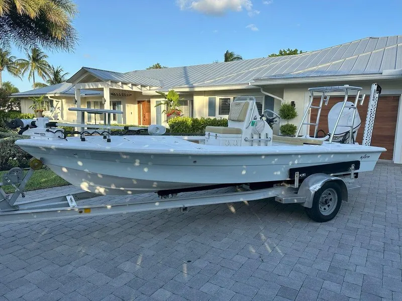 Slide: The Image of 2022 Blacktip Boatworks 18 Flats boat on a trailer in front of a house. - 6