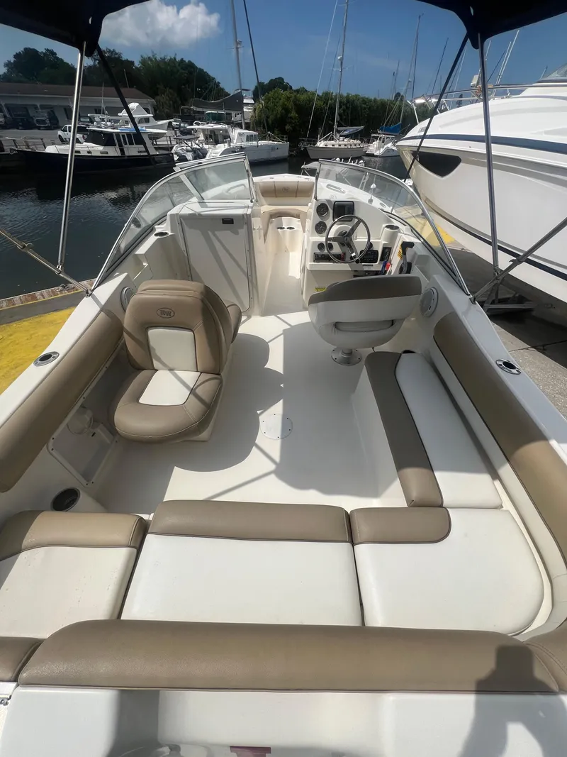 Slide: The Image of 2014 Key West 203 DFS boat interior with beige and white seating at a marina. - 4