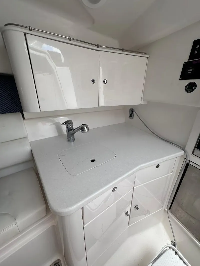 Slide: The Image of 2016 Intrepid 375 Walkaround boat interior kitchen with white cabinets and countertop. - 7