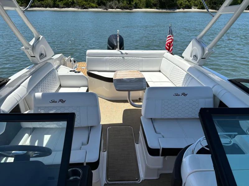 Slide: The Image of 2023 Sea Ray SDX 270 Outboard boat interior with white seating and table on water. - 16