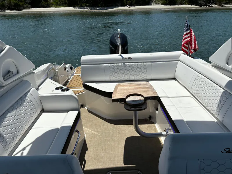 Slide: The Image of 2023 Sea Ray SDX 270 Outboard boat interior with white seating and wooden table. - 17