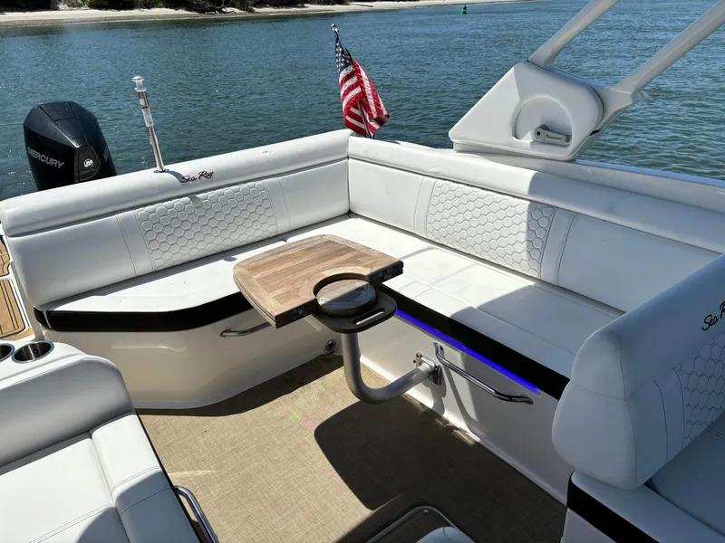 Slide: The Image of 2023 Sea Ray SDX 270 Outboard boat interior with white seating and wooden table. - 18