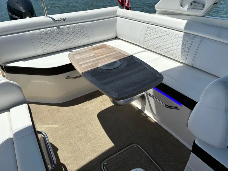 Slide: The Image of 2023 Sea Ray SDX 270 Outboard boat interior with white seating and wooden table. - 19