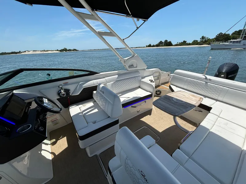 Slide: The Image of 2023 Sea Ray SDX 270 Outboard boat interior with white seating and table on the water. - 30