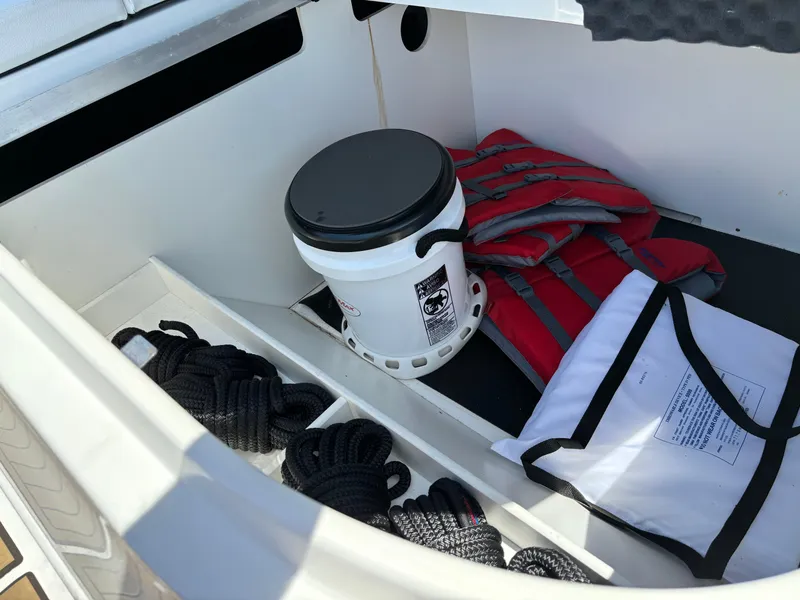 Slide: The Image of Storage compartment of a 2023 Sea Ray SDX 270 Outboard with life jackets, ropes, and a bucket. - 36