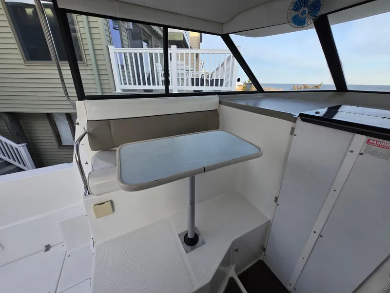 Slide: The Image of Bayliner 2859 Ciera Express 2000 interior with seating and table, docked near buildings. - 15