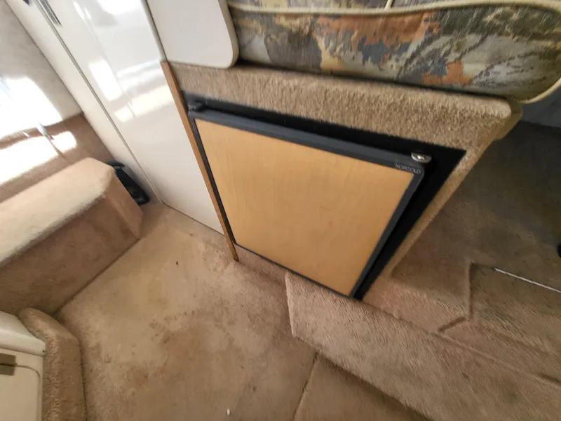 Slide: The Image of Interior of 2000 Bayliner 2859 Ciera Express, featuring compact fridge and carpeted flooring. - 18