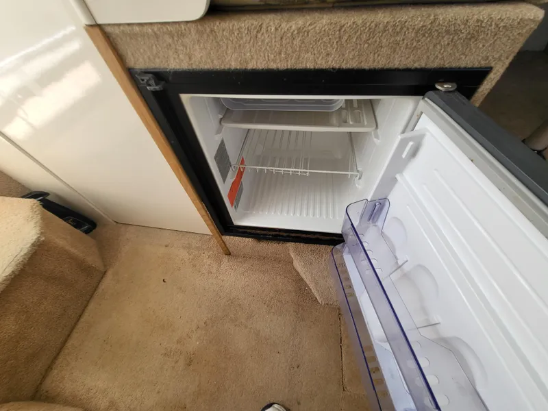 Slide: The Image of Open mini fridge inside 2000 Bayliner 2859 Ciera Express boat, showing interior shelves. - 19