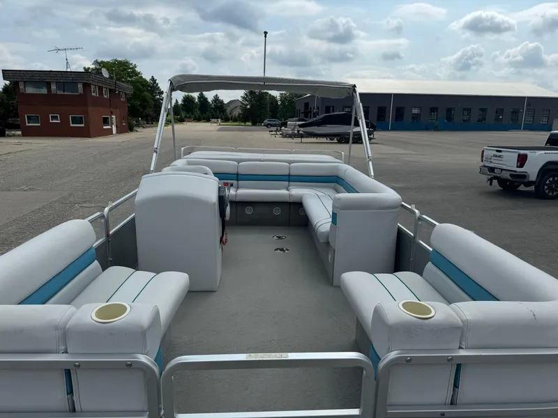 Slide: The Image of 1993 Harris 200 Classic pontoon boat with spacious seating, parked in an open lot. - 5