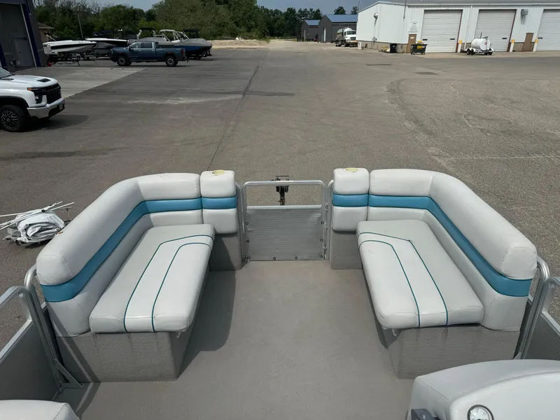 Slide: The Image of 1993 Harris 200 Classic pontoon boat with white and blue seating, parked in a lot. - 7