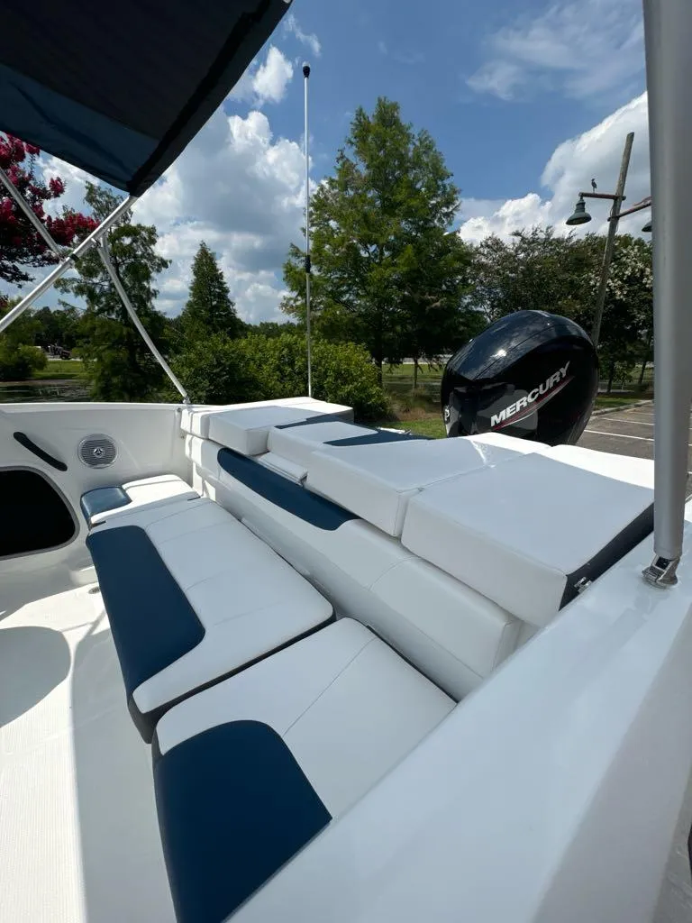 Slide: The Image of 2024 Tahoe 185 S boat with Mercury engine, white and blue seating, outdoor setting. - 6