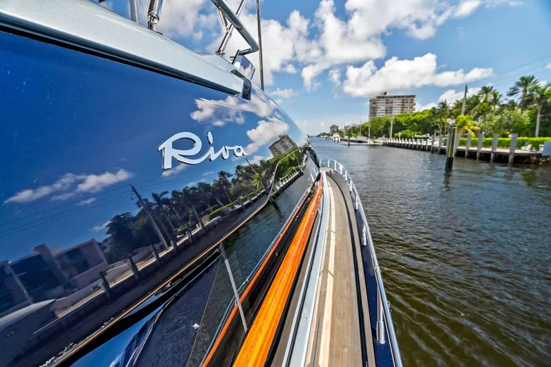 Slide: The Image of Riva 66' Ribelle 2020 yacht reflecting water and sky, docked near palm trees and buildings. - 10