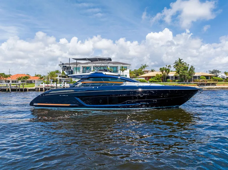 Slide: The Image of 2020 Riva 66' Ribelle luxury yacht cruising near waterfront homes. - 2
