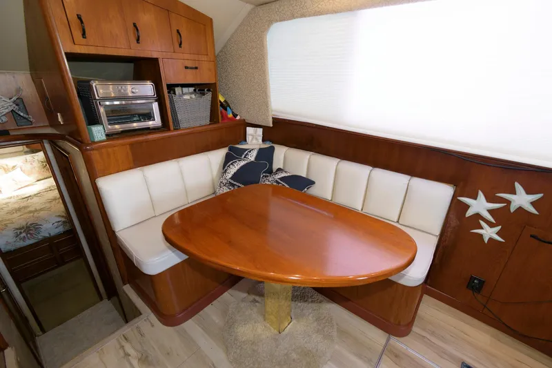 Slide: The Image of 1994 Ocean Yachts 44 Aft Cabin Motor Yacht interior dining area with wooden table and white seating. - 15