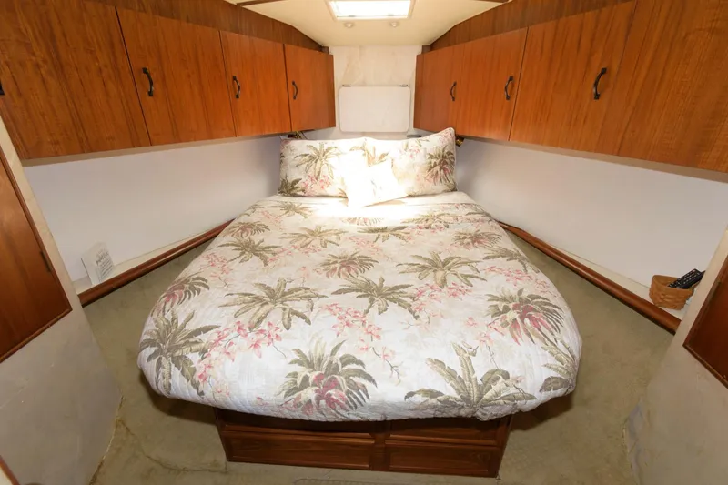 Slide: The Image of 1994 Ocean Yachts 44 Aft Cabin Motor Yacht bedroom with tropical-themed bedding and wooden cabinets. - 22