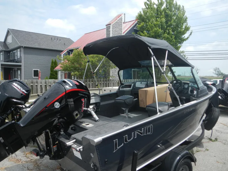 Slide: The Image of 2024 Lund 1775 Impact XS Sport boat with outboard motor, parked outdoors. - 11