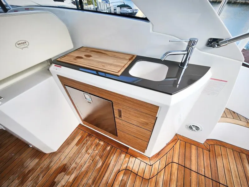 Slide: The Image of 2024 Sessa Marine C36 OB yacht kitchenette with sink, wooden cabinetry, and cutting board. - 17
