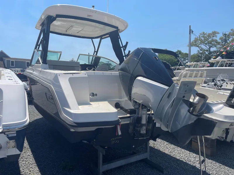 Slide: The Image of 2023 Boston Whaler 240 Vantage boat with outboard motor, docked on gravel. - 15