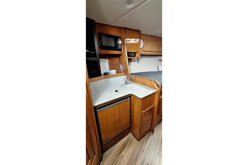 Slide: The Image of 2001 Topaz Express boat interior with kitchenette, featuring wood cabinetry, sink, and microwave. - 34