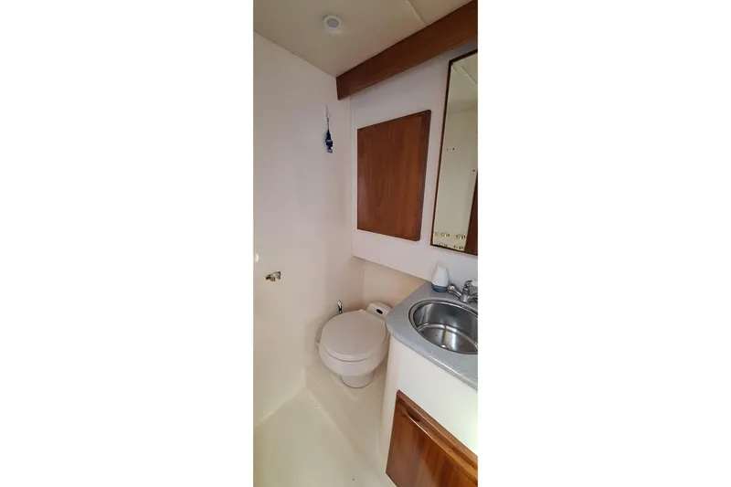 Slide: The Image of Compact bathroom in 2001 Topaz Express boat with toilet, sink, and wooden cabinetry. - 39