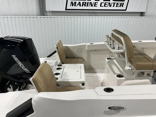 Slide: The Image of 2024 Bayliner T22CC boat interior with Mercury engine, featuring beige seating and fishing rod holders. - 11
