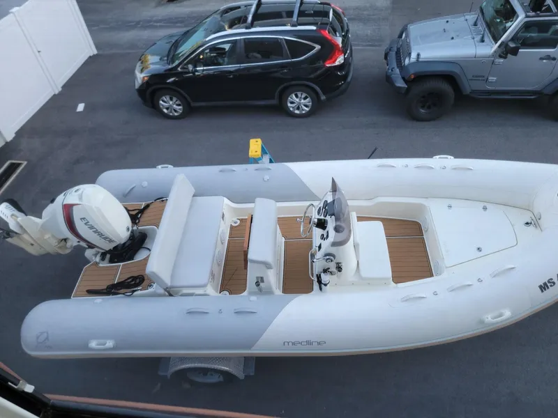 Slide: The Image of 2014 Zodiac Medline 580 inflatable boat on trailer, parked near two cars. - 4
