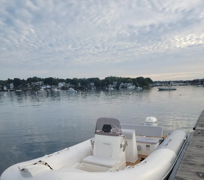 Slide: The Image of 2014 Zodiac Medline 580 boat docked by a calm waterfront under a cloudy sky. - 7