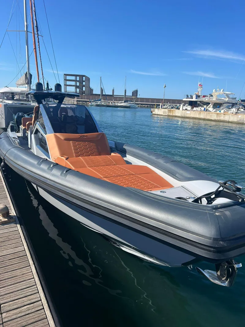 Slide: The Image of Modern DNA 46 boat docked at marina, 2025 model, sleek design with orange seating. - 12