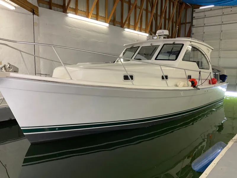 The Image of 2000 Mainship Pilot boat docked indoors, white hull with green stripe. - 0