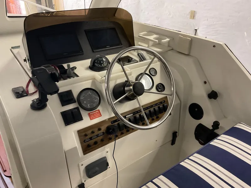 Slide: The Image of 2000 Mainship Pilot boat helm with steering wheel, gauges, and striped seating. - 15