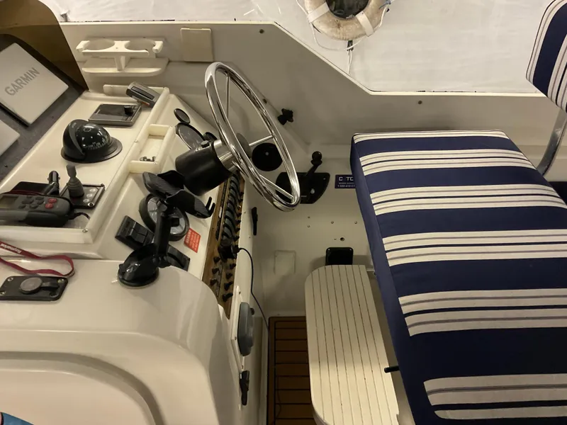 Slide: The Image of 2000 Mainship Pilot boat helm with striped seating and navigation equipment. - 17