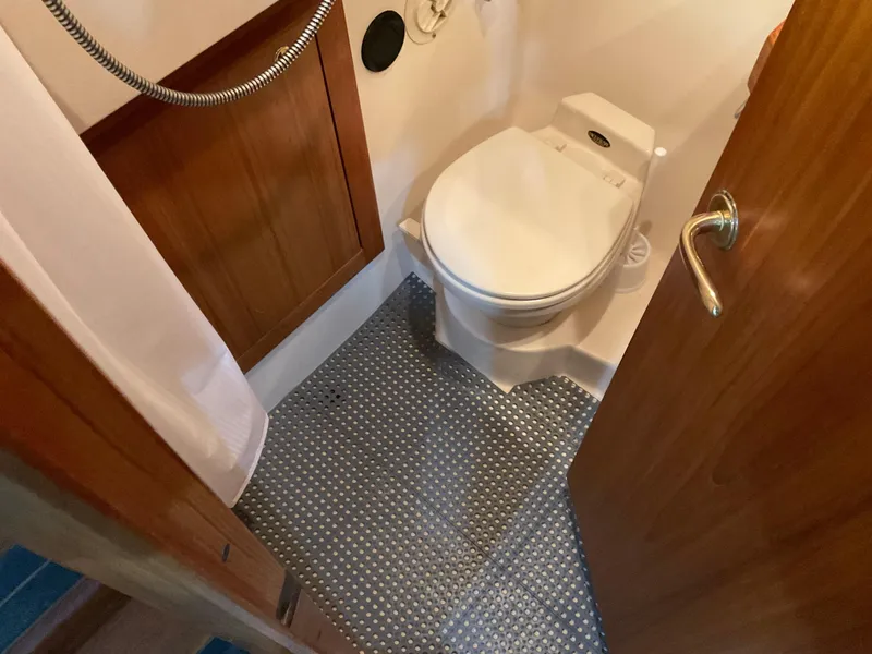 Slide: The Image of 2000 Mainship Pilot bathroom with toilet, wood paneling, and textured flooring. - 18