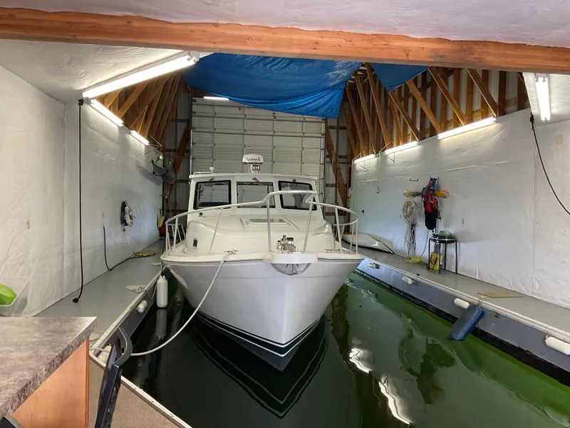 Slide: The Image of 2000 Mainship Pilot boat docked in a covered boathouse with green water. - 2