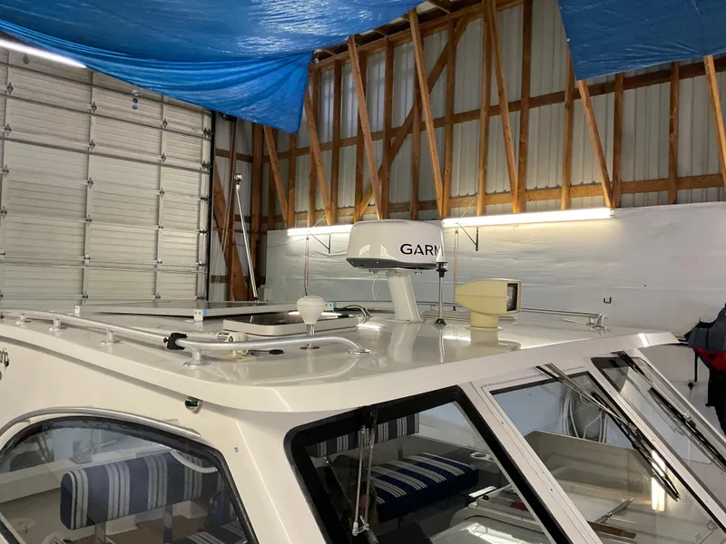 Slide: The Image of 2000 Mainship Pilot boat in storage, featuring radar and striped interior seating. - 7