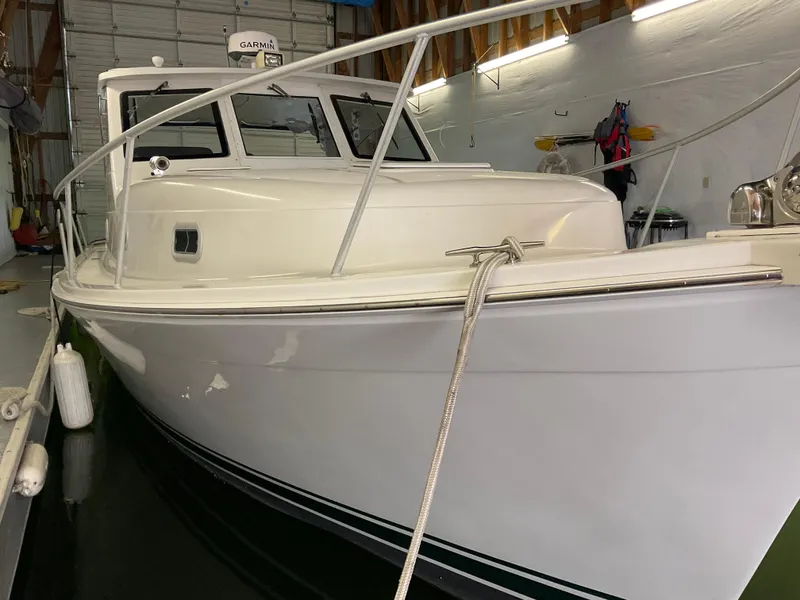 Slide: The Image of 2000 Mainship Pilot boat docked indoors, showcasing sleek white hull and cabin. - 8