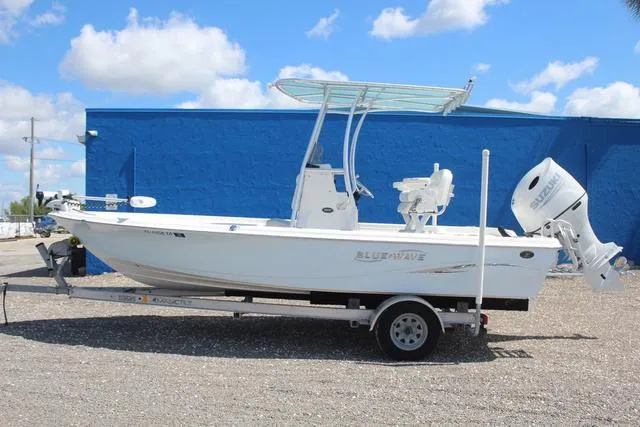Slide: The Image of 2021 Blue Wave 2000 Pure Bay boat on trailer, parked outdoors under blue sky. - 7