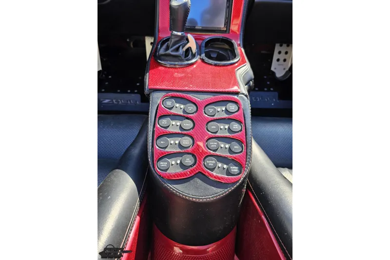 Slide: The Image of 2010 MTI 44 Corvette interior console with red carbon fiber finish and control switches. - 51
