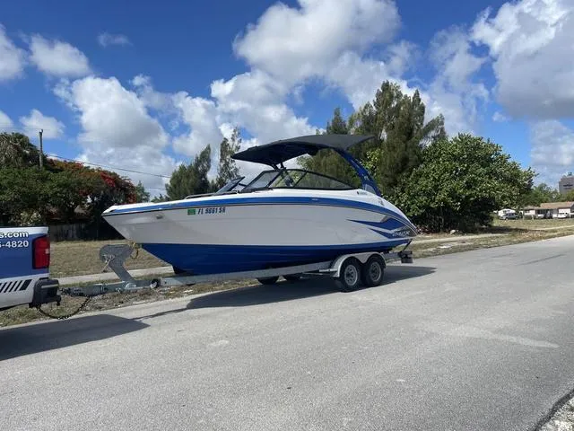 Slide: The Image of 2020 Yamaha Boats 242X on trailer, blue and white, parked on a sunny day. - 11