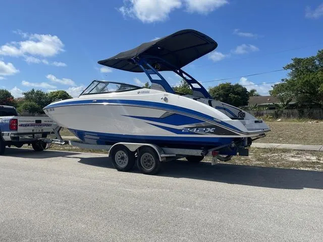 Slide: The Image of 2020 Yamaha Boats 242X on trailer, blue and white, parked on a sunny day. - 4