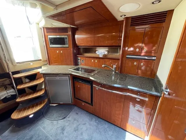 Slide: The Image of 2005 Sea Ray 390 Sundancer yacht kitchen with wooden cabinetry and modern appliances. - 38