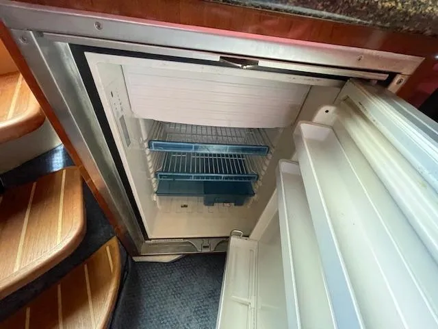 Slide: The Image of Open refrigerator inside 2005 Sea Ray 390 Sundancer yacht, showing shelves and door compartments. - 48