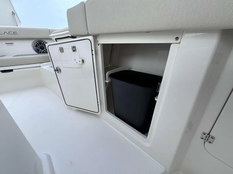 Slide: The Image of Storage compartment on 2024 Solace 32 CS boat with open door and black bin. - 11