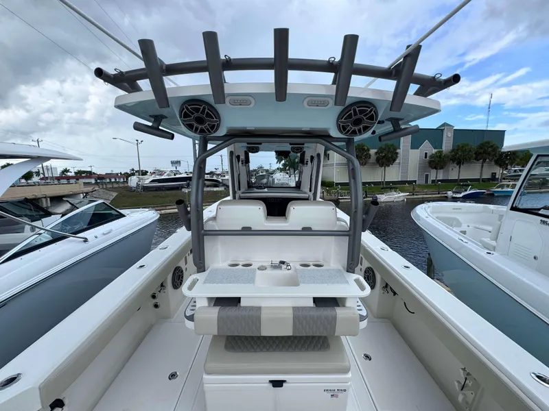 Slide: The Image of 2024 Solace 32 CS center console boat at marina, featuring seating and rod holders. - 21