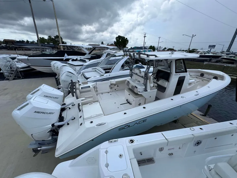 Slide: The Image of 2024 Solace 32 CS boat with twin Mercury engines docked at a marina. - 33