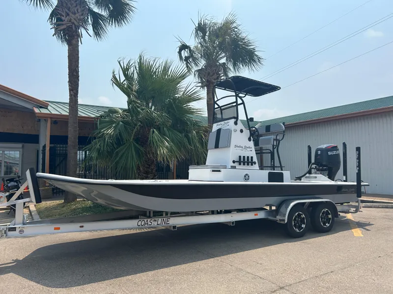 The Image of 2025 Shallow Stalker 240 RC Elite boat on trailer, parked near palm trees. - 0